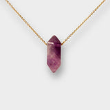 Natural Amethyst crystal necklace. The necklace features a pointed amethyst crystal pendant attached to a gold chain, creating a stunning and eye-catching piece of jewelry.