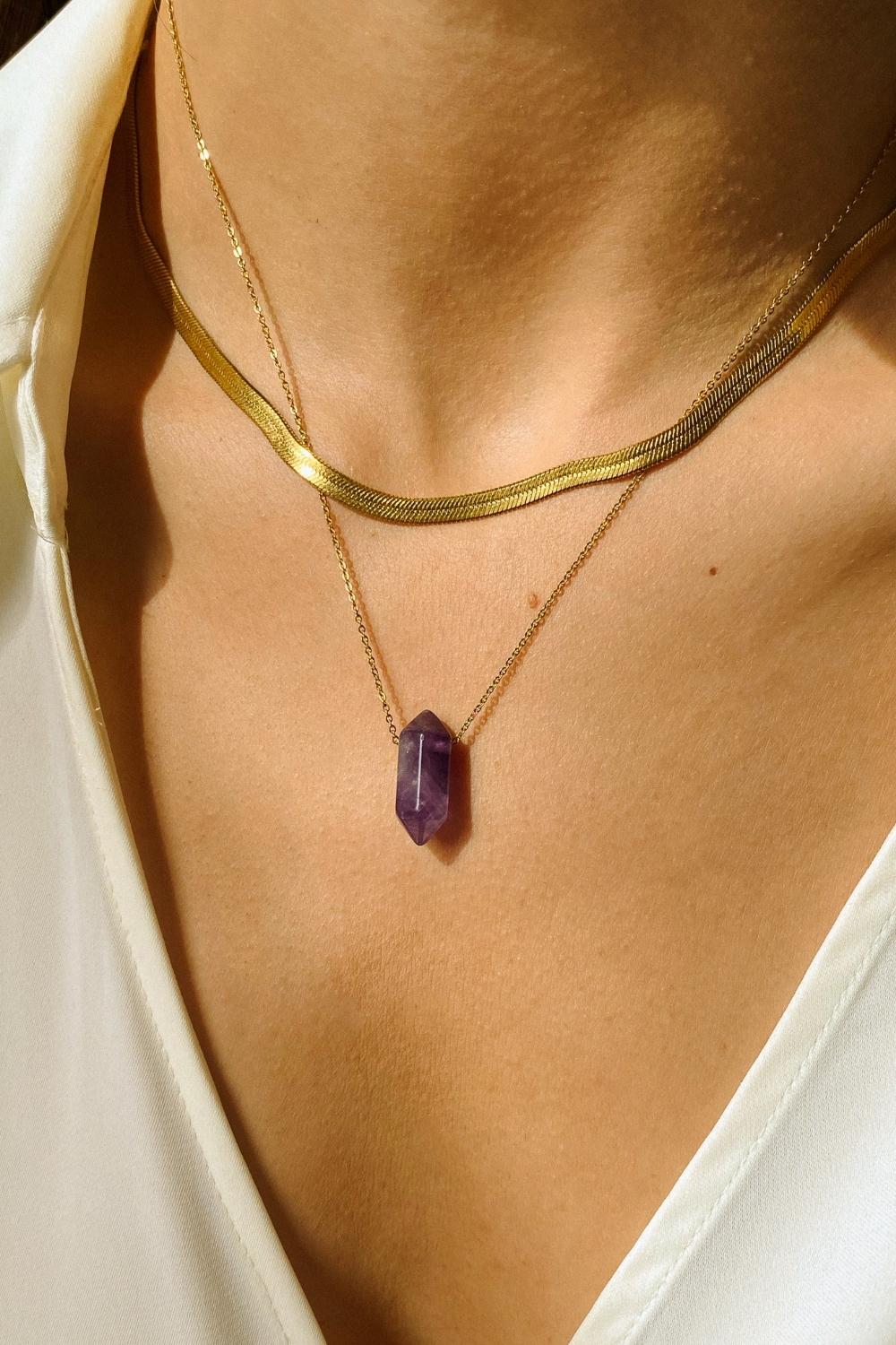 Natural Amethyst crystal necklace. The first necklace features a pointed amethyst crystal pendant, while the second necklace features a delicate gold snake chain. Together, the necklaces create a stunning layered look that adds sophistication and elegance to any outfit.