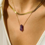 Natural Amethyst crystal necklace. The first necklace features a pointed amethyst crystal pendant, while the second necklace features a delicate gold snake chain. Together, the necklaces create a stunning layered look that adds sophistication and elegance to any outfit.