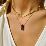 Natural Amethyst crystal necklace. The first necklace features a pointed amethyst crystal pendant, while the second necklace features a delicate gold paper clip chain. Together, the necklaces create a stunning layered look that adds sophistication and elegance to any outfit.