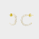 beaded pearl hoop earrings in 18k gold plated silver. The earrings feature a classic hoop design adorned with delicate beads and lustrous pearls. The gold plated silver adds a touch of elegance and sophistication to the design. The pearls are beautifully strung along the hoops, adding a timeless and glamorous element.