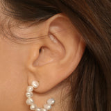 beaded pearl hoop earrings in 18k gold plated silver. The earrings feature a classic hoop design adorned with delicate beads and lustrous pearls. The gold plated silver adds a touch of elegance and sophistication to the design. The pearls are beautifully strung along the hoops, adding a timeless and glamorous element.