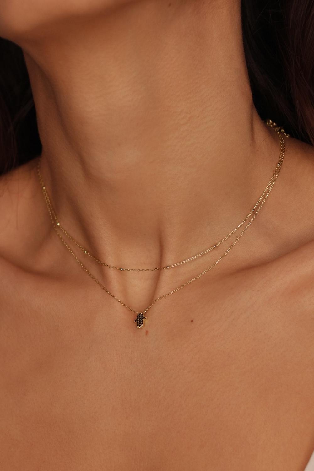 A satellite choker necklace in 18k gold plated silver. The necklace features a dainty chain with evenly spaced small beads, resembling satellites. The beads are made of gold and delicately interlinked. The necklace sits snugly around the neck, creating a trendy and minimalist look