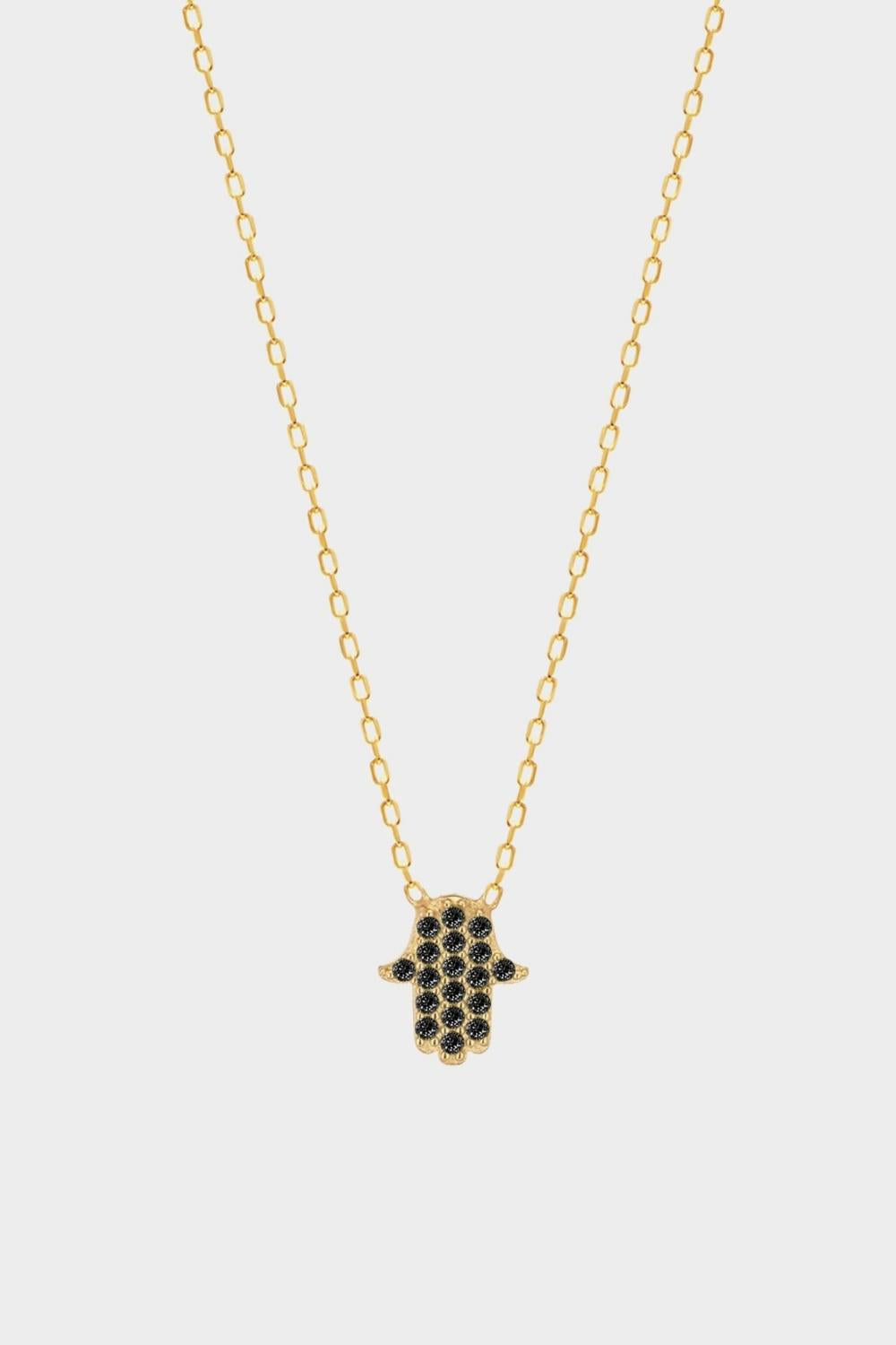 a black Hamsa hand charm necklace in 18k gold plated silver. The necklace features a delicate chain with a beautifully designed Hamsa hand charm pendant. The Hamsa hand symbol is believed to bring protection, good luck, and ward off evil. The necklace is designed to be worn comfortably and can be adjusted to fit different neck sizes.