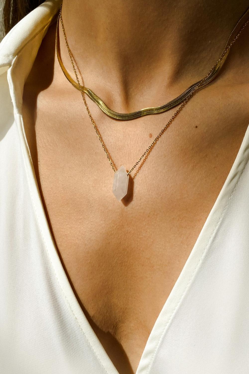 Clear Quartz crystal necklace. The first necklace features a pointed clear quartz crystal pendant, while the second necklace features a delicate gold snake chain. Together, the necklaces create a stunning layered look that adds sophistication and elegance to any outfit.