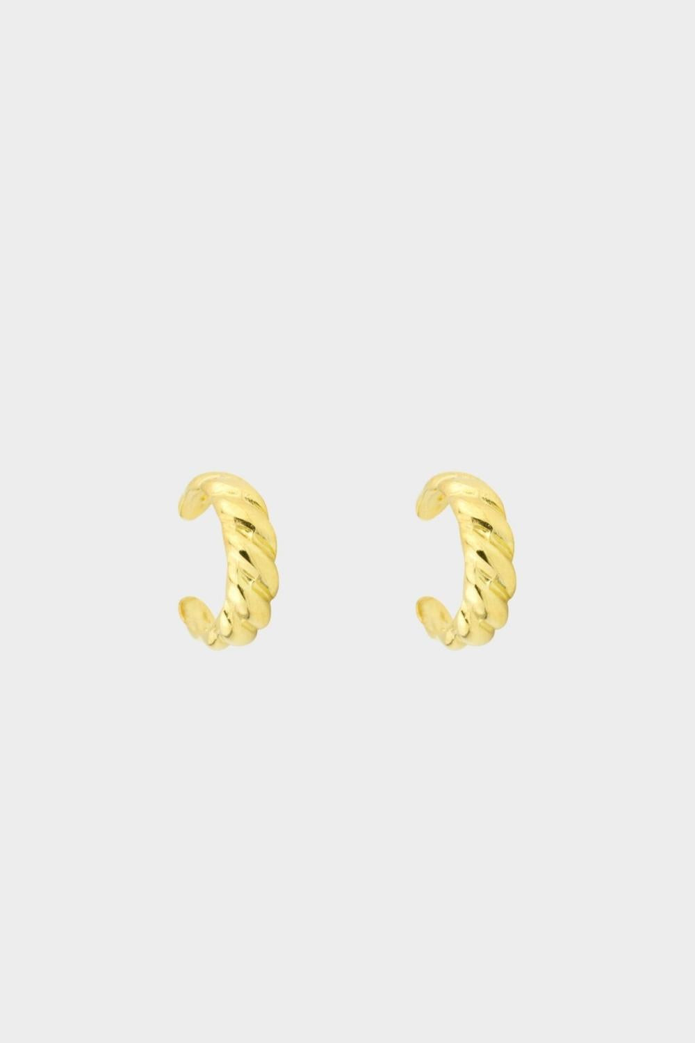 a croissant ear cuff in 18k gold plated silver. The ear cuff features a unique croissant-shaped design that wraps around the earlobe. It is made of high-quality gold plated silver with a polished finish, giving it a luxurious and elegant look. The cuff is designed to be worn without the need for a piercing, making it a trendy and versatile accessory.