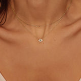 A layered necklaces featuring an evil eye charm necklace in gold and a satellite chain choker. The set includes a delicate 18k gold plated chain with an intricately designed evil eye charm pendant. Alongside the evil eye charm necklace, a satellite chain choker is also included, adding a trendy and minimalist touch. The satellite chain choker features small, evenly spaced interlinked gold beads, creating a delicate and stylish look.