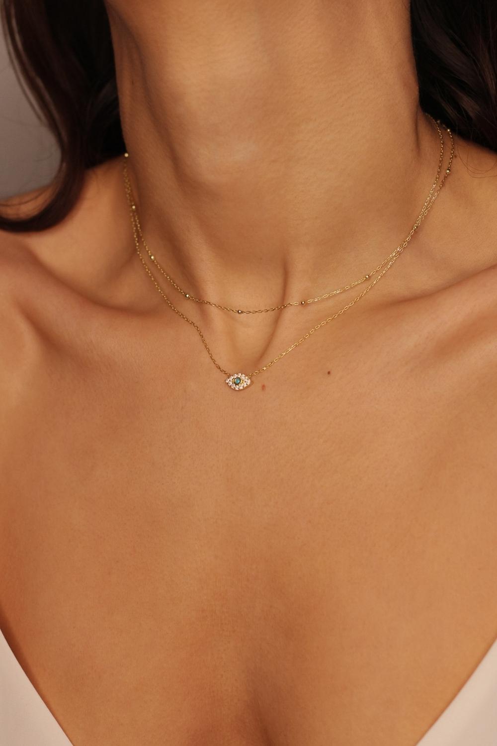 A satellite choker necklace in 18k gold plated silver. The necklace features a dainty chain with evenly spaced small beads, resembling satellites. The beads are made of gold and delicately interlinked. The necklace sits snugly around the neck, creating a trendy and minimalist look
