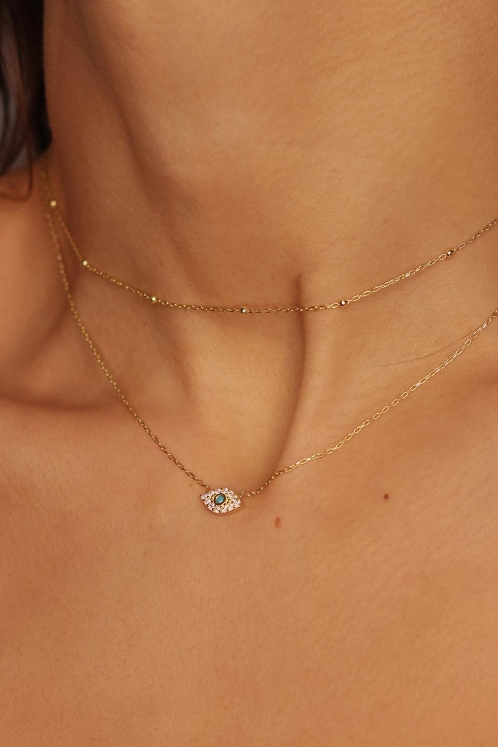 A satellite choker necklace in 18k gold plated silver. The necklace features a dainty chain with evenly spaced small beads, resembling satellites. The beads are made of gold and delicately interlinked. The necklace sits snugly around the neck, creating a trendy and minimalist look