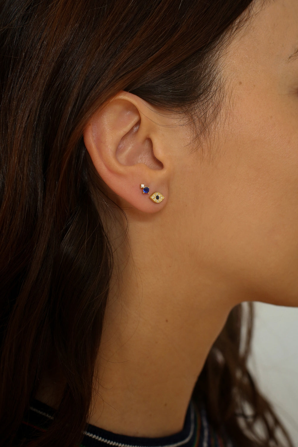 Evil eye stud earrings in 18k gold plated. The earrings feature a traditional evil eye design with a vibrant blue center. The evil eye symbol is believed to provide protection against negative energy and bring good luck. The studs are made of high-quality gold plated material with a polished finish, giving them a luxurious and elegant look.