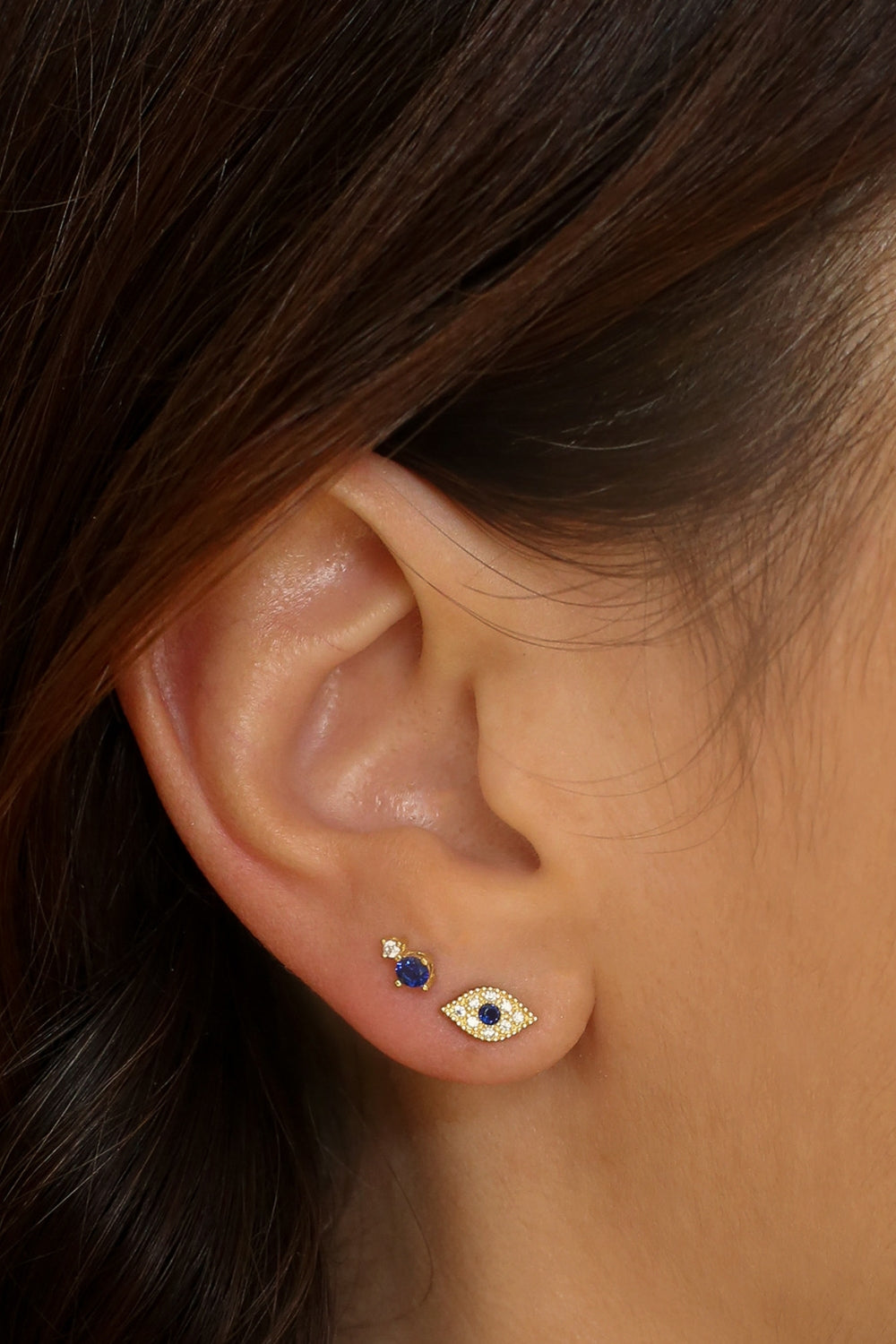 Evil eye stud earrings in 18k gold plated. The earrings feature a traditional evil eye design with a vibrant blue center. The evil eye symbol is believed to provide protection against negative energy and bring good luck. The studs are made of high-quality gold plated material with a polished finish, giving them a luxurious and elegant look.