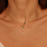 A Green Hamsa hand charm necklace in 18k gold plated silver. The necklace features a delicate chain with a beautifully designed Hamsa hand charm pendant. The Hamsa hand symbol is believed to bring protection, good luck, and ward off evil. The necklace is designed to be worn comfortably and can be adjusted to fit different neck sizes.