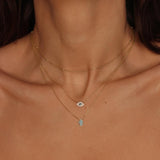 A blue Hamsa hand charm necklace in 18k gold plated silver. The necklace features a delicate chain with a beautifully designed Hamsa hand charm pendant. The Hamsa hand symbol is believed to bring protection, good luck, and ward off evil. The necklace is designed to be worn comfortably and can be adjusted to fit different neck sizes.