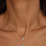 A layered necklaces featuring an evil eye charm necklace, hamsa necklace in gold and a satellite chain choker. The set includes a delicate 18k gold plated chain with an intricately designed evil eye charm pendant. Alongside the evil eye charm necklace, a satellite chain choker is also included, adding a trendy and minimalist touch. The satellite chain choker features small, evenly spaced interlinked gold beads, creating a delicate and stylish look.