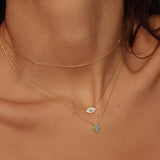 A blue Hamsa hand charm necklace in 18k gold plated silver. The necklace features a delicate chain with a beautifully designed Hamsa hand charm pendant. The Hamsa hand symbol is believed to bring protection, good luck, and ward off evil. The necklace is designed to be worn comfortably and can be adjusted to fit different neck sizes.