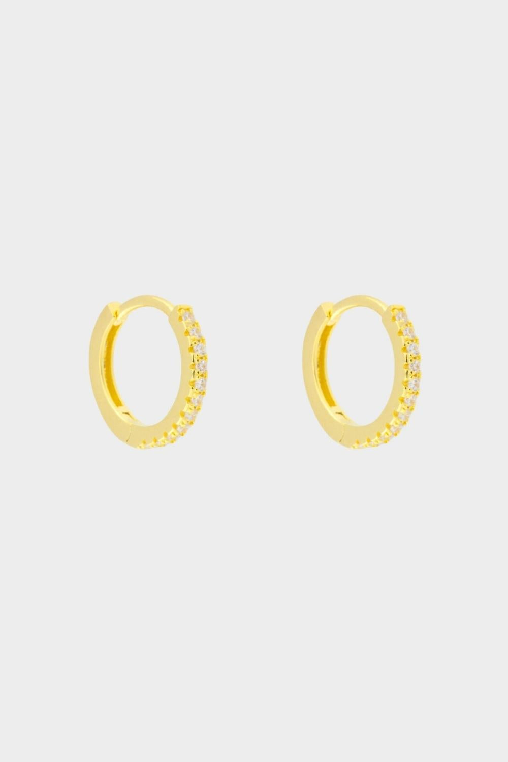 diamond huggie hoops in 18k gold plated silver. The earrings feature a classic huggie-style design adorned with sparkling diamonds. The diamonds are meticulously set along the front of the hoops, adding a touch of luxury and glamour. The hoops are made of high-quality gold plated silver and have a polished finish.