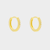 diamond huggie hoops in 18k gold plated silver. The earrings feature a classic huggie-style design adorned with sparkling diamonds. The diamonds are meticulously set along the front of the hoops, adding a touch of luxury and glamour. The hoops are made of high-quality gold plated silver and have a polished finish.