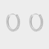 diamond huggie hoops in sterling silver. The earrings feature a classic huggie-style design adorned with sparkling diamonds. The diamonds are meticulously set along the front of the hoops, adding a touch of luxury and glamour. The hoops are made of high-quality silver and have a polished finish.
