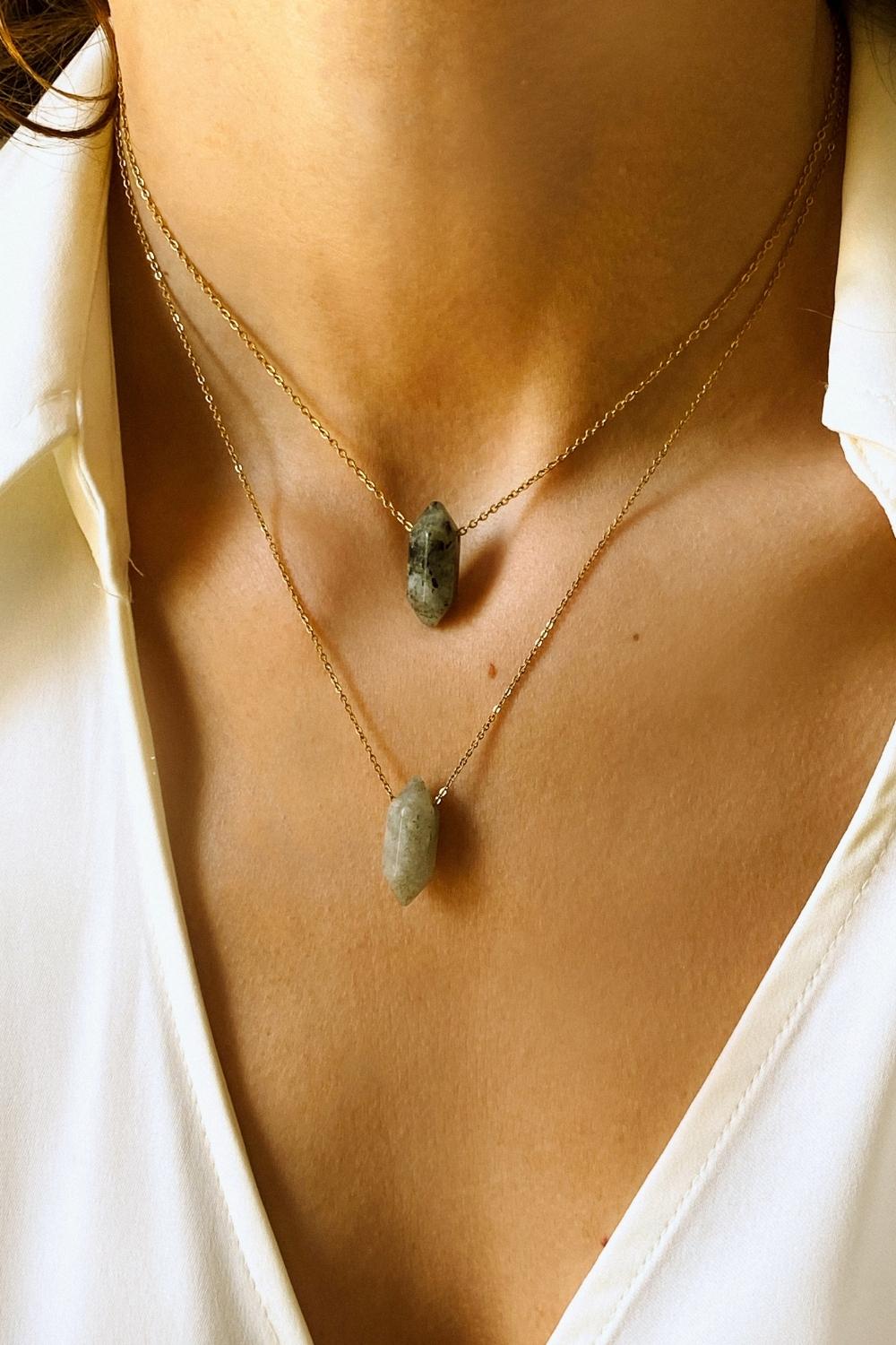 Labradorite crystal necklace. The necklace features a pointed labradorite crystal pendant attached to a gold chain, creating a stunning and eye-catching piece of jewelry.