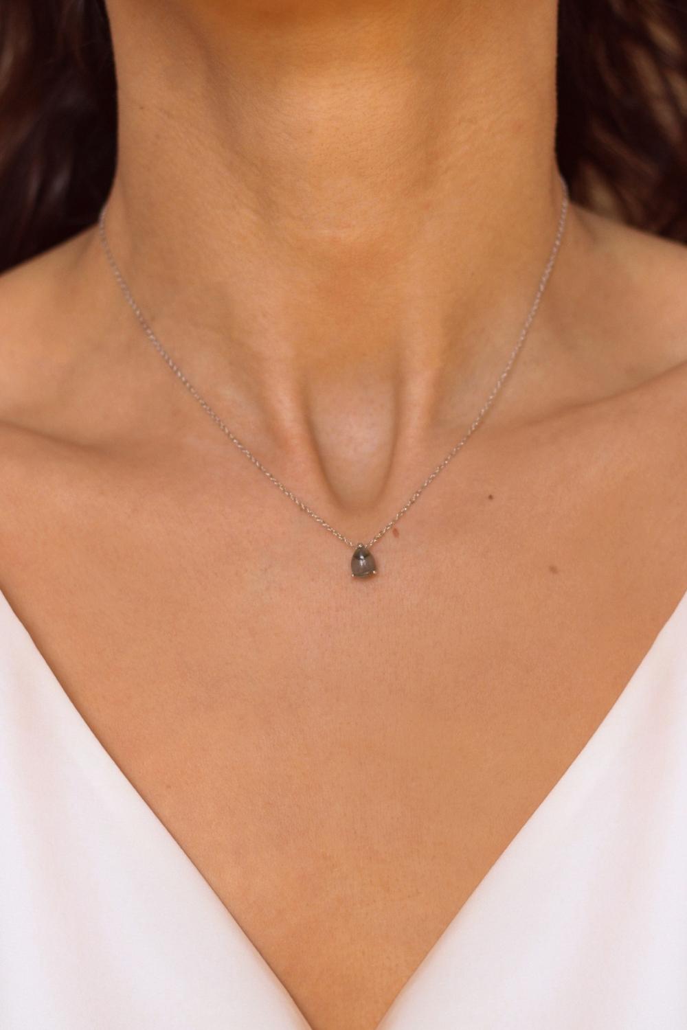 A labradorite stone pendant necklace in sterling silver. The necklace features a stunning labradorite stone pendant that is beautifully crafted and set in a silver bezel. The labradorite stone exhibits vibrant shades of grey with unique patterns, creating a captivating and natural look. The pendant is suspended from a delicate gold chain, adding elegance and sophistication to the necklace