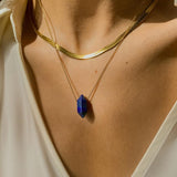Lapis lazuli crystal necklace. The first necklace features a pointed lapis lazuli crystal pendant, while the second necklace features a delicate gold snake chain. Together, the necklaces create a stunning layered look that adds sophistication and elegance to any outfit.