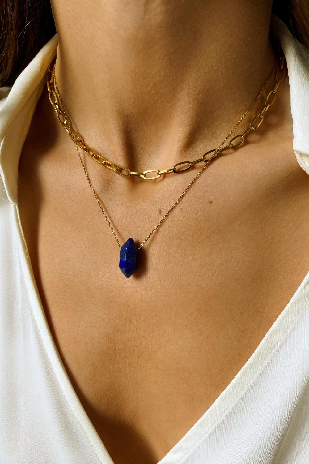 Lapis lazuli crystal necklace. The first necklace features a pointed lapis lazuli crystal pendant, while the second necklace features a delicate gold paper clip chain. Together, the necklaces create a stunning layered look that adds sophistication and elegance to any outfit.