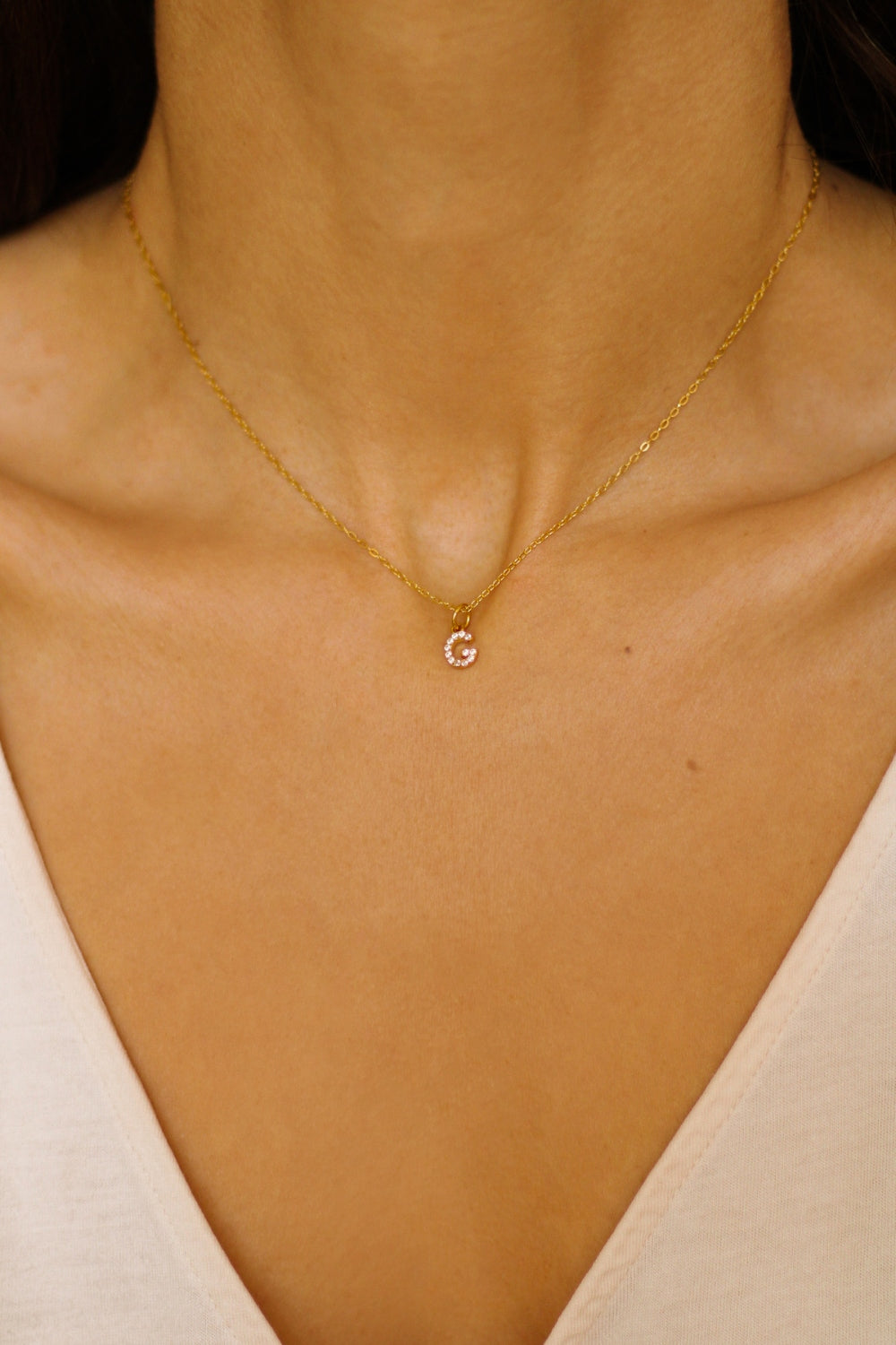 An initial pendant necklace in 18k gold plated silver. The necklace features a delicate gold chain, with a pendant in the shape of a single letter G from the alphabet. The pendant is intricately designed, showcasing the initial with a stylish and elegant font. Perfect for gifting or adding a personal touch to any outfit.