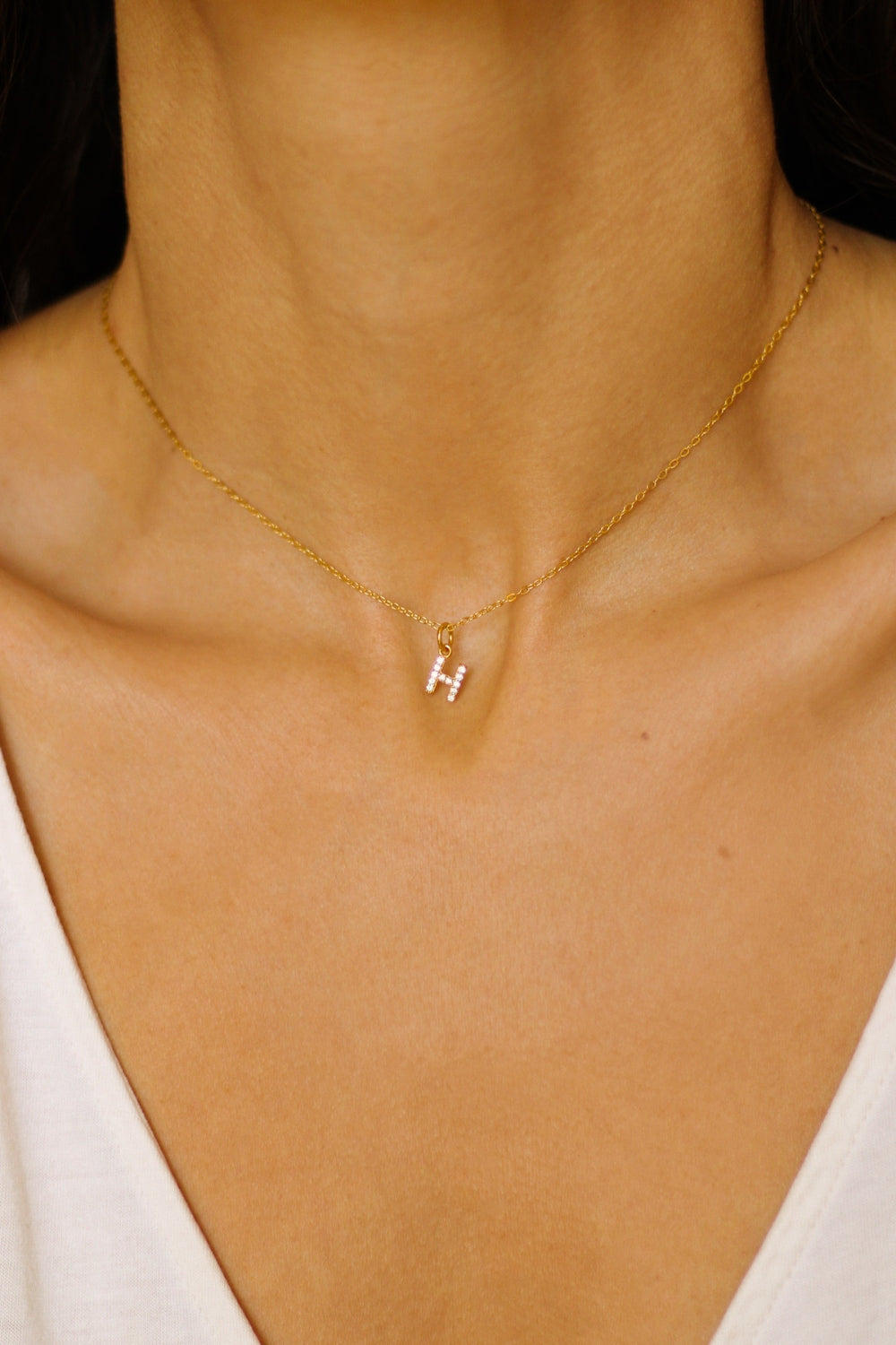 An initial pendant necklace in 18k gold plated silver. The necklace features a delicate gold chain, with a pendant in the shape of a single letter H from the alphabet. The pendant is intricately designed, showcasing the initial with a stylish and elegant font. Perfect for gifting or adding a personal touch to any outfit.