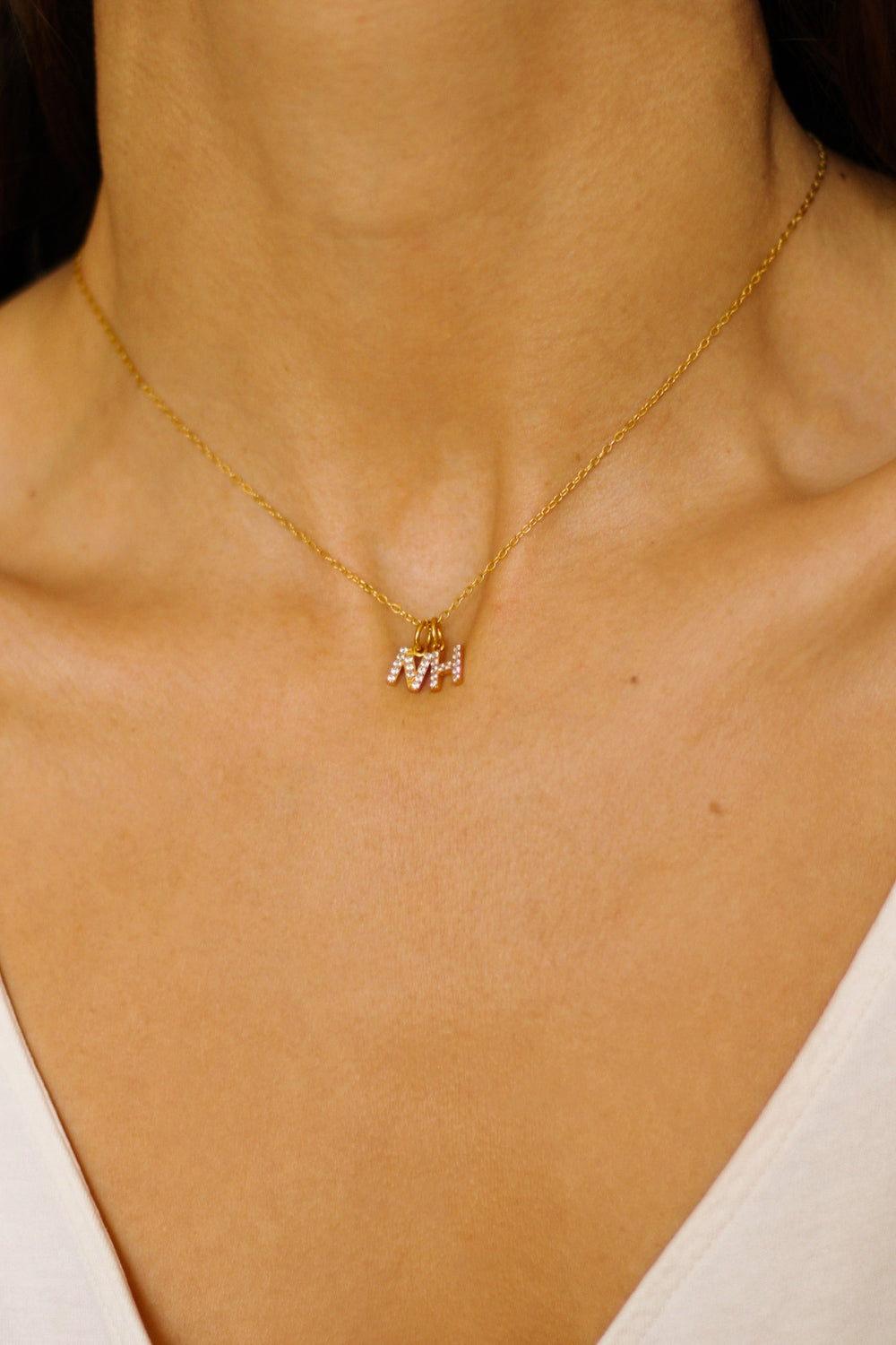 An initial pendant necklace in 18k gold plated silver. The necklace features a delicate gold chain, with a pendant in the shape of a single letter N and H from the alphabet. The pendant is intricately designed, showcasing the initial with a stylish and elegant font. Perfect for gifting or adding a personal touch to any outfit.