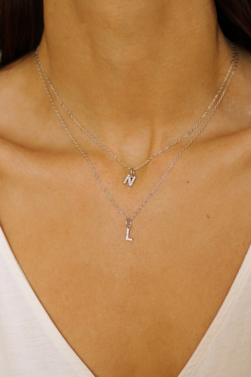 An initial pendant necklace in sterling silver. The necklace features a delicate silver chain, with a pendant in the shape of a single letter L and N from the alphabet. The pendant is intricately designed, showcasing the initial with a stylish and elegant font. Perfect for gifting or adding a personal touch to any outfit.