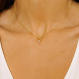 An initial pendant necklace in 18k gold plated silver. The necklace features a delicate gold chain, with a pendant in the shape of a single letter T from the alphabet. The pendant is intricately designed, showcasing the initial with a stylish and elegant font. Perfect for gifting or adding a personal touch to any outfit.