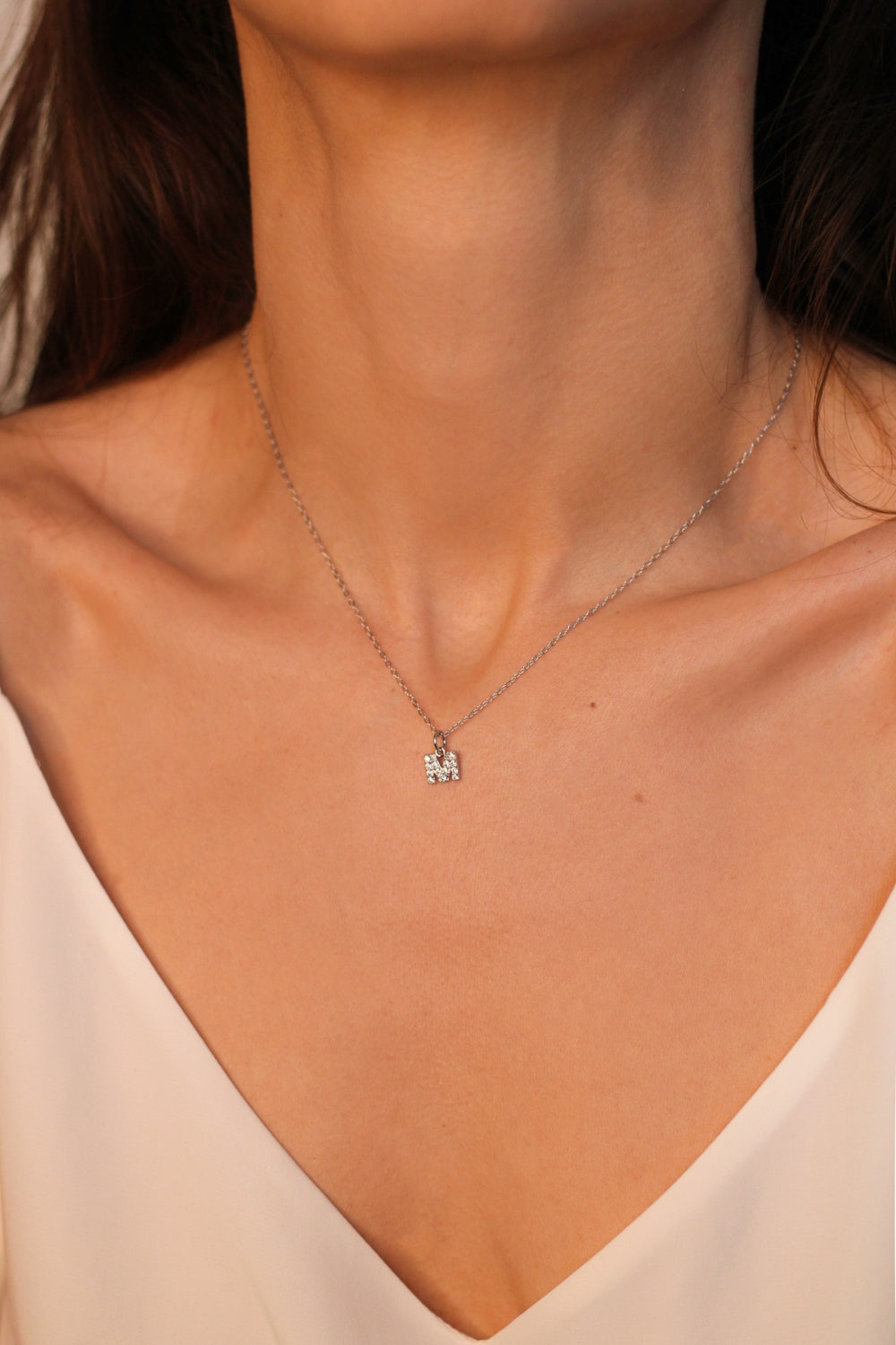 An initial pendant necklace in sterling silver. The necklace features a delicate silver chain, with a pendant in the shape of a single letter M from the alphabet. The pendant is intricately designed, showcasing the initial with a stylish and elegant font. Perfect for gifting or adding a personal touch to any outfit.