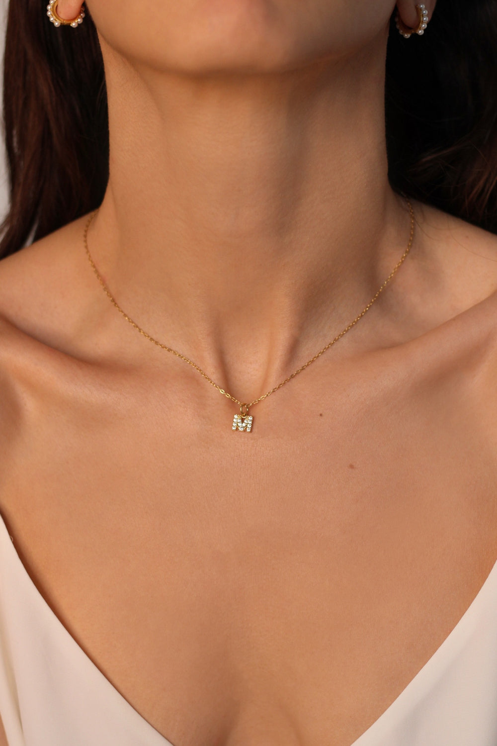 An initial pendant necklace in 18k gold plated silver. The necklace features a delicate gold chain, with a pendant in the shape of a single letter M from the alphabet. The pendant is intricately designed, showcasing the initial with a stylish and elegant font. Perfect for gifting or adding a personal touch to any outfit.