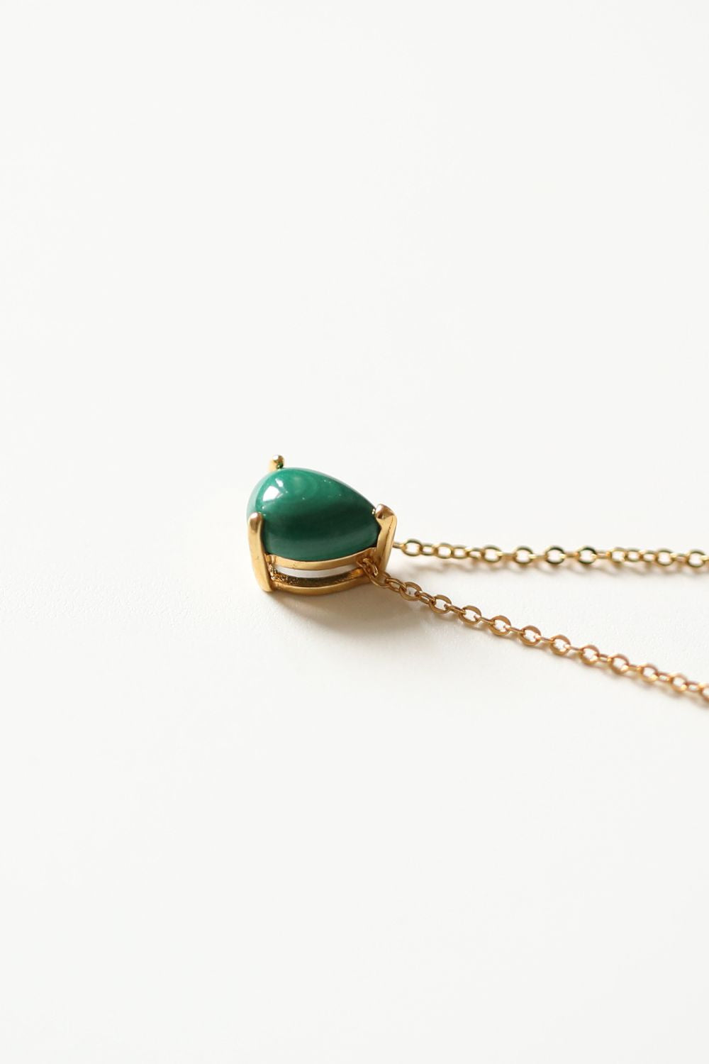 A malachite stone pendant necklace in 18k gold plated silver. The necklace features a stunning malachite stone pendant that is beautifully crafted and set in a gold bezel. The malachite stone exhibits vibrant shades of green with unique patterns, creating a captivating and natural look. The pendant is suspended from a delicate gold chain, adding elegance and sophistication to the necklace