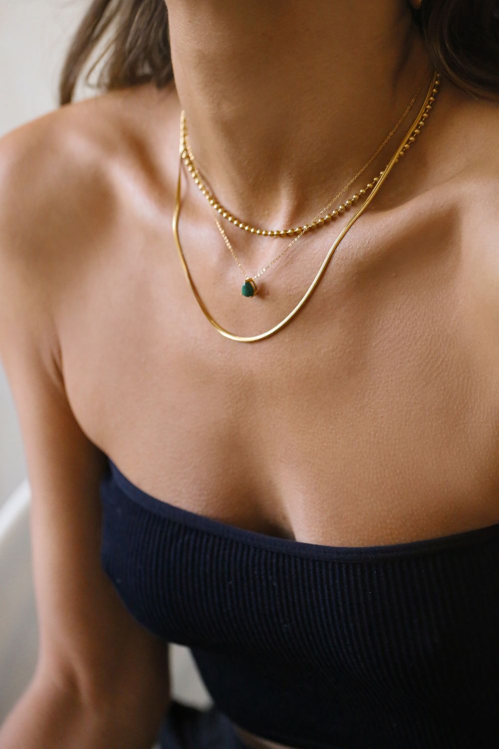 A malachite stone pendant necklace in 18k gold plated silver. The necklace features a stunning malachite stone pendant that is beautifully crafted and set in a gold bezel. The malachite stone exhibits vibrant shades of green with unique patterns, creating a captivating and natural look. The pendant is suspended from a delicate gold chain, adding elegance and sophistication to the necklace