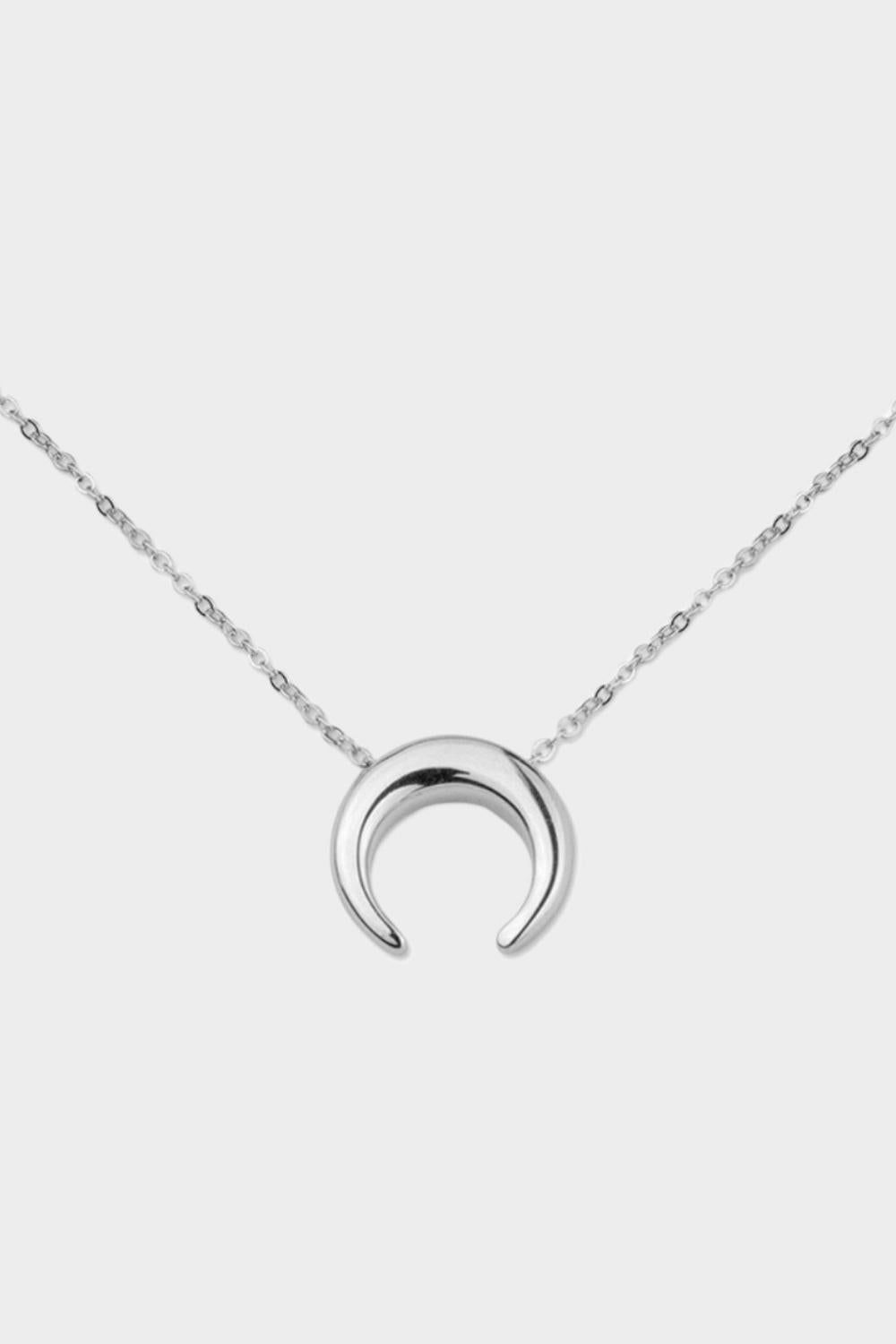 A moon necklace in sterling silver. The necklace features a delicate silver chain with a pendant in the shape of a crescent moon. The necklace is perfect for those who love celestial-inspired jewelry, and makes for an elegant and stylish accessory that can be worn on any occasion.