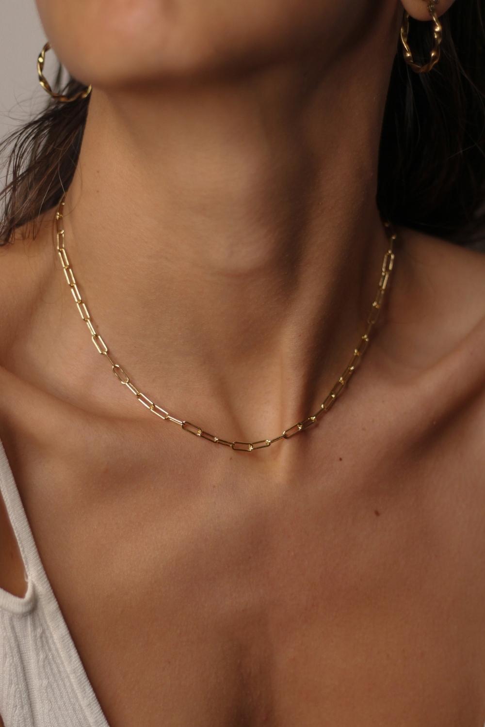 18k gold plated over sterling silver paper clip chain choker. The choker is composed of interlocking paper clip-shaped links, with each link carefully plated in 18k gold for a luxurious and radiant shine. The paper clip chain design gives the necklace a trendy and contemporary look. The choker is designed to sit comfortably around the neck, creating a stylish and fashionable accessory that can be worn alone or layered with other necklaces