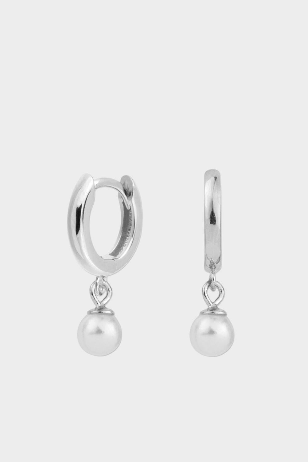 Drop pearl huggies in sterling silver. The earrings feature a huggie-style design with drop-shaped pearls. The pearls are lustrous and elegantly suspended from the gold plated silver hoops. The hoops have a sleek and polished finish. These earrings are versatile and can be worn for both casual and formal occasions