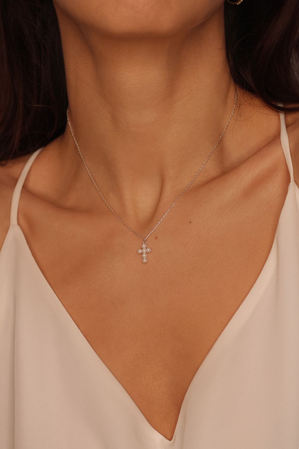 Pearl cross pendant necklace in 925 sterling silver. The necklace features a delicate silver chain with a pendant in the shape of a cross. The cross pendant is adorned with lustrous white pearls, adding a touch of elegance and femininity to the design. The necklace is crafted with meticulous attention to detail, creating a timeless and religious-inspired piece of jewelry. It can be worn as a symbolic accessory or as a fashionable statement piece.