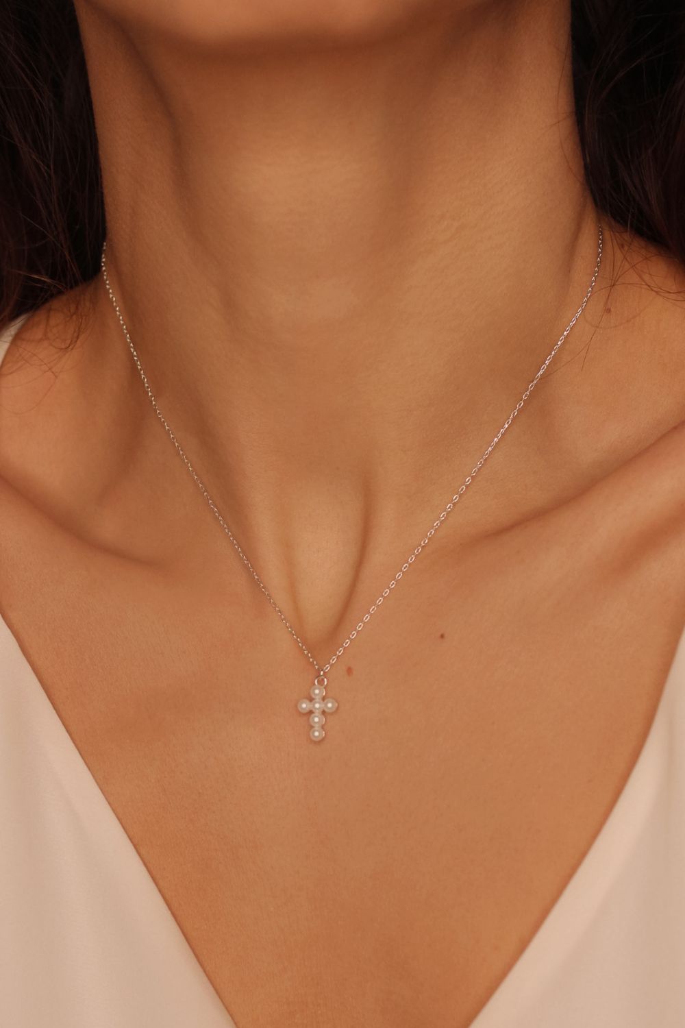 Pearl cross pendant necklace in 925 sterling silver. The necklace features a delicate silver chain with a pendant in the shape of a cross. The cross pendant is adorned with lustrous white pearls, adding a touch of elegance and femininity to the design. The necklace is crafted with meticulous attention to detail, creating a timeless and religious-inspired piece of jewelry. It can be worn as a symbolic accessory or as a fashionable statement piece.