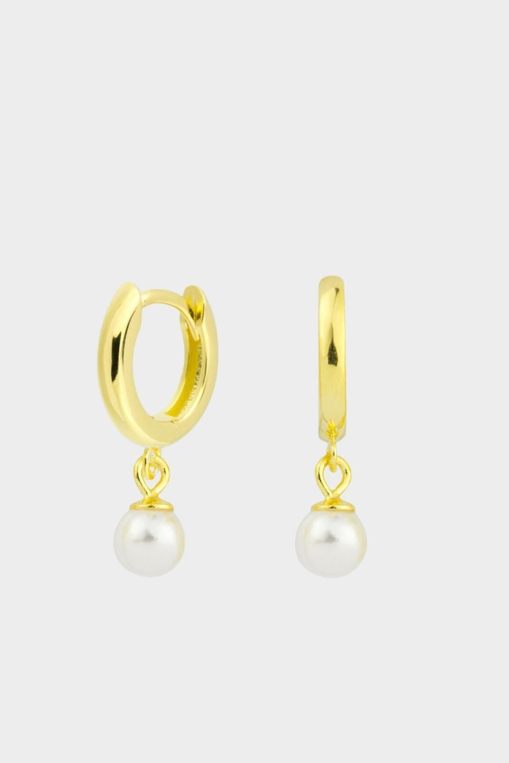Drop pearl huggies in 18k gold plated silver. The earrings feature a huggie-style design with drop-shaped pearls. The pearls are lustrous and elegantly suspended from the gold plated silver hoops. The hoops have a sleek and polished finish. These earrings are versatile and can be worn for both casual and formal occasions