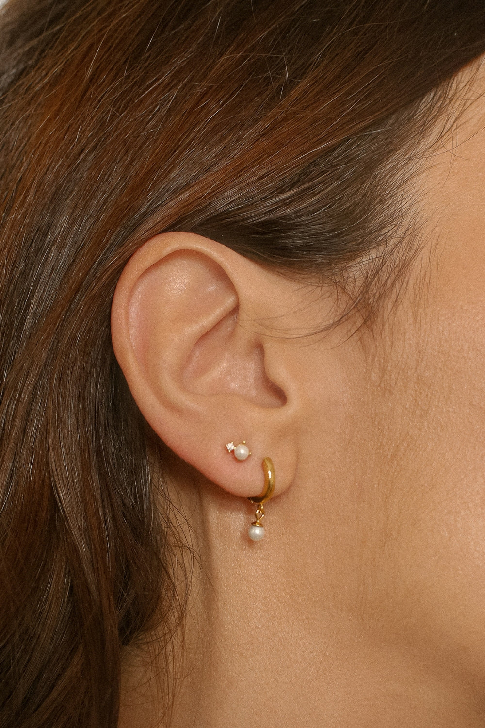 Drop pearl huggies in 18k gold plated silver. The earrings feature a huggie-style design with drop-shaped pearls. The pearls are lustrous and elegantly suspended from the gold plated silver hoops. The hoops have a sleek and polished finish. These earrings are versatile and can be worn for both casual and formal occasions