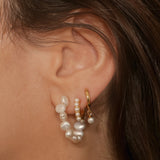 Drop pearl huggies in 18k gold plated silver. The earrings feature a huggie-style design with drop-shaped pearls. The pearls are lustrous and elegantly suspended from the gold plated silver hoops. The hoops have a sleek and polished finish. These earrings are versatile and can be worn for both casual and formal occasions