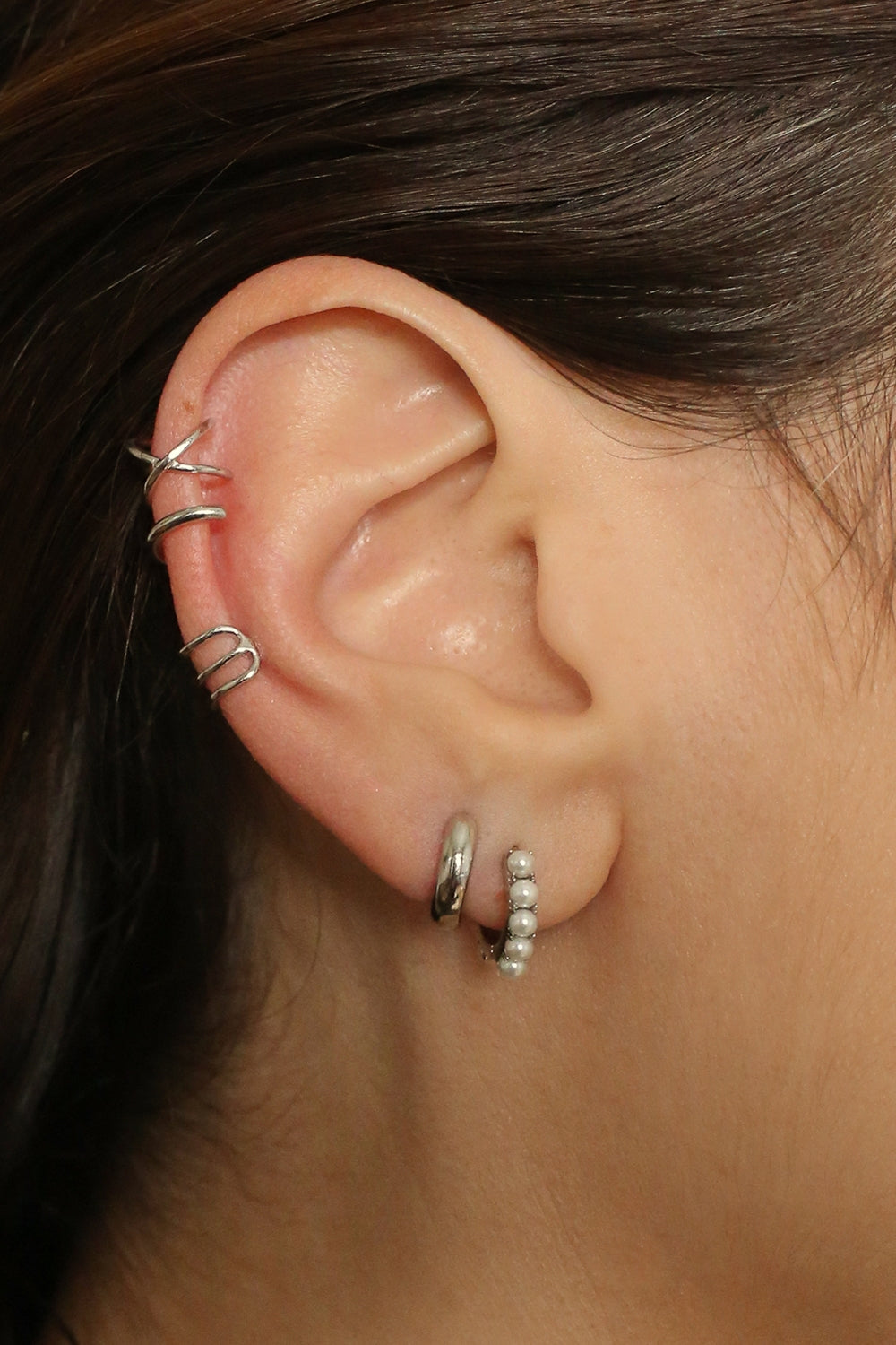 Beaded pearl huggies in sterling silver. The earrings feature a classic hoop design adorned with delicate beads and lustrous pearls. The silver adds a touch of elegance and sophistication to the design. The pearls are beautifully strung along the hoops, adding a timeless and glamorous element.