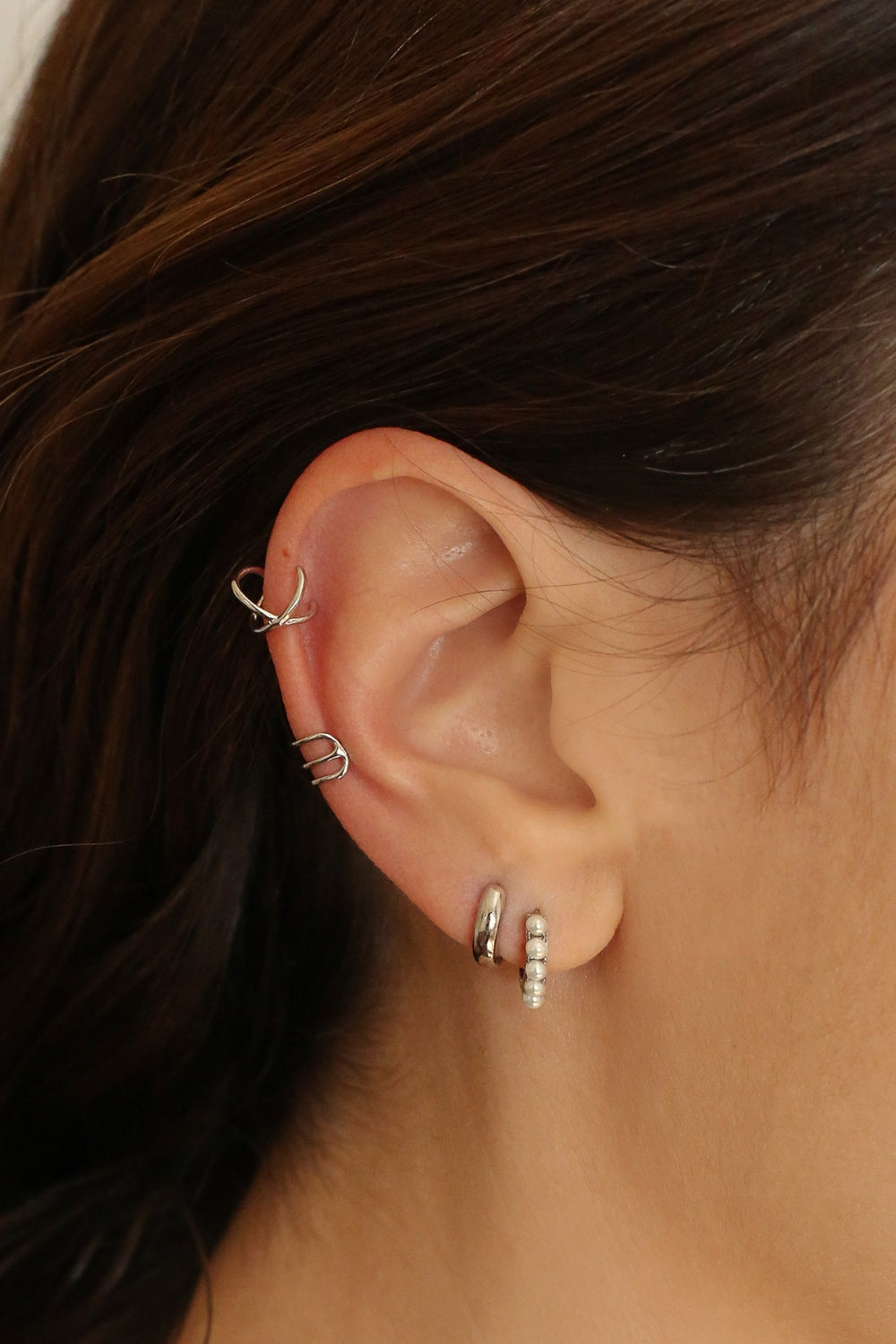 Beaded pearl huggies in sterling silver. The earrings feature a classic hoop design adorned with delicate beads and lustrous pearls. The silver adds a touch of elegance and sophistication to the design. The pearls are beautifully strung along the hoops, adding a timeless and glamorous element.