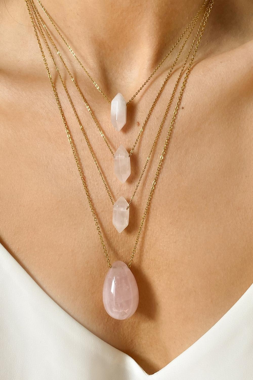 Rose Quartz crystal necklace. The first necklace features a pointed rose quartz crystal pendant, while the second necklace features a delicate gold paper clip chain. Together, the necklaces create a stunning layered look that adds sophistication and elegance to any outfit.