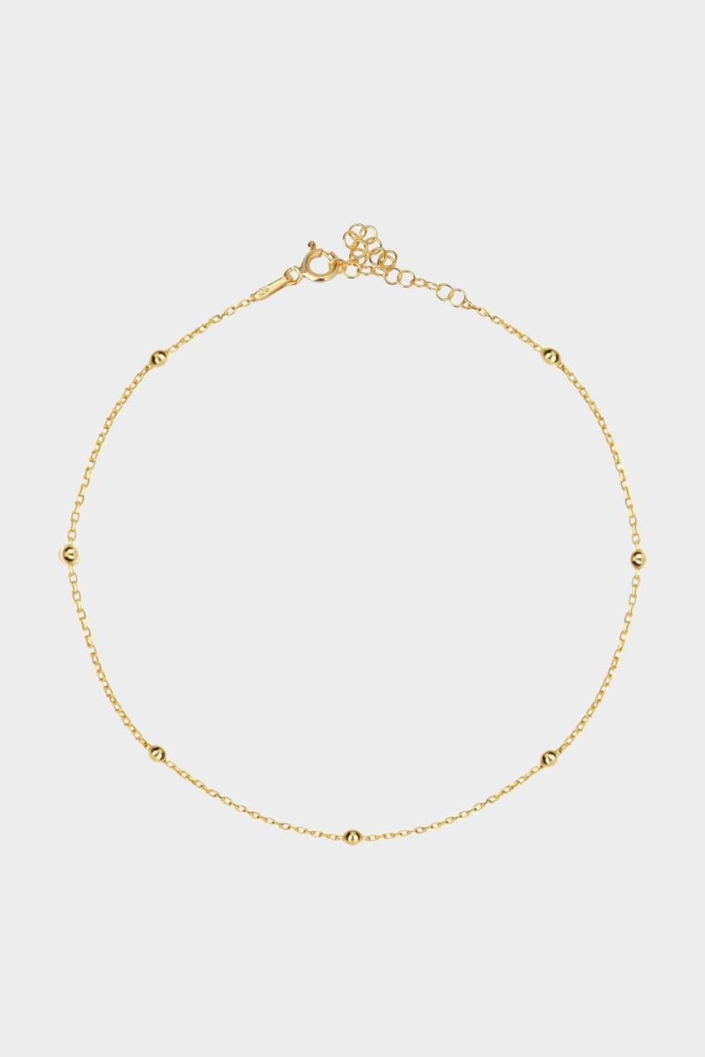 A satellite choker necklace in 18k gold plated silver. The necklace features a dainty chain with evenly spaced small beads, resembling satellites. The beads are made of gold and delicately interlinked. The necklace sits snugly around the neck, creating a trendy and minimalist look.