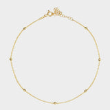 A satellite choker necklace in 18k gold plated silver. The necklace features a dainty chain with evenly spaced small beads, resembling satellites. The beads are made of gold and delicately interlinked. The necklace sits snugly around the neck, creating a trendy and minimalist look.