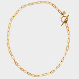 18k gold plated toggle choker necklace. The necklace features a sleek and minimalistic design, with a single chain crafted from high-quality metal and plated with 18k gold for a luxurious finish. The centerpiece of the necklace is a toggle closure, consisting of a small, decorative gold ring and a bar that fits through it to secure the necklace. This chic and elegant accessory adds a touch of sophistication to any outfit