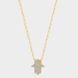 A White Hamsa hand charm necklace in 18k gold plated silver. The necklace features a delicate chain with a beautifully designed Hamsa hand charm pendant. The Hamsa hand symbol is believed to bring protection, good luck, and ward off evil. The necklace is designed to be worn comfortably and can be adjusted to fit different neck sizes.